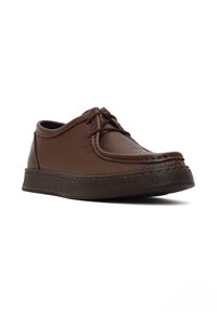 Zapatos de cuero marrón con una superficie texturada, punta redonda y diseño de cordones. Cuenta con una suela de goma con un patrón de banda de rodadura sencillo.