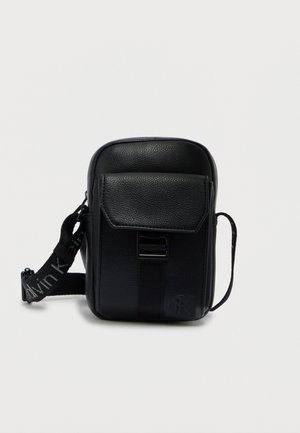 Sort læder crossbody-taske med tekstureret overflade, justerbar rem, forflap og en logodetalje. Kompakt rektangulær form.