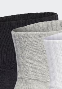 Tri parovi rebrastih čarapa: crne, sive i bijele. Svaka ima mekanu teksturu i elastične rubove, ističući jednostavan, jednoličan dizajn.