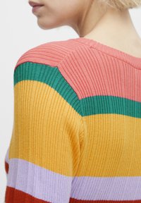 Pull en maille côtelée multicolore avec des rayures verticales rose, vert, jaune, violet et rouge ; finition texturée avec un col rond.