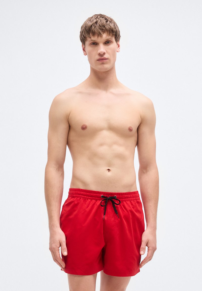 Κόκκινα μαγιό βερμούδα με ελαστική μέση και μαύρο κορδόνι, με ομαλή υφή και σχεδιασμό μήκους ως το μέσο του μηρού.