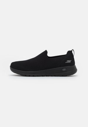Black slip-on sneaker with a breathable mesh upper, round toe, and cushioned rubber sole. Features a logo on the side.