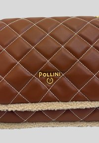 Borsa in pelle marrone trapuntata con cuciture bianche, dotata di un logo "Pollini" in oro e un accento in pelliccia shearling beige alla base.