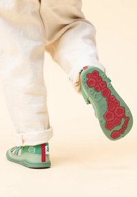 Sandali verdi con suola in gomma caratterizzata da un motivo esagonale, dettagli colorati e un design della cinghia testurizzato. Parte superiore in morbido tessuto.