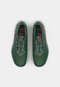 Green athletic shoes with a textured upper, reflective accents, gray detailing, and red branding. Features laces and a cushioned sole.