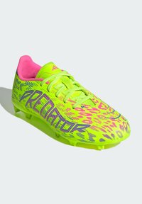 Botines de fútbol en color amarillo neón con acentos rosas, que presentan una parte superior texturizada, patrones audaces y tacos moldeados para mayor tracción.