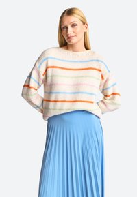 Strickpullover mit horizontalen Streifen in Pink, Blau, Orange und Gr�ün auf einem cremefarbenen Hintergrund; kombiniert mit einem gefalteten hellblauen Rock.