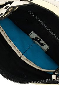 Bustina in tessuto con esterno color crema, rivestimento interno blu e dettagli neri. Presenta una chiusura con cerniera e un'etichetta in pelle con il logo all'interno.