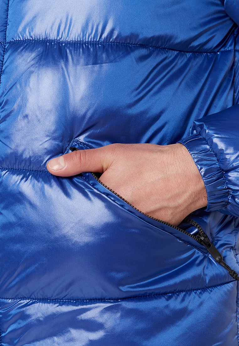 Blaues, gepolstertes Jackenmaterial mit glänzender Oberfläche, ausgestattet mit einer Seitentasche und elastischen Bündchen. Das Material sieht weich und glatt aus.