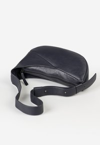Borsa a tracolla in pelle blu navy con forma curva, chiusura a zip e tracolla regolabile. Texture liscia con dettagli di design minimalisti.
