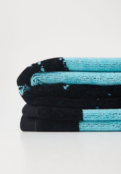 Three towels stacked. The top is turquoise with black accents, the middle is solid black, and the bottom is black with turquoise details.