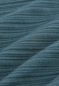 Tessuto blu testurizzato con sottili strisce verticali, caratterizzato da un morbido motivo a coste. Il materiale appare leggero e intrecciato.