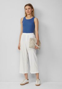 Blauwe geribbelde tanktop, witte cropped linnen broek, beige gevlochten tas met een riem, witte sneakers met een lichtbruine zool.