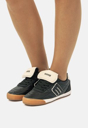 Schwarze synthetische Sneakers mit runder Zehenform, weißen Klettverschlussriemen, Gummisohle und gestepptem Design an den Seiten.