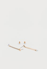 Σκουλαρίκια χρυσού τόνου με διαφανείς στρας· περιλαμβάνει σχέδιο καρφίτσας και αλυσίδα με διακοσμητικό στρας, διαθέτοντας διαφανείς λαστιχένιες πίσω πλευρές.