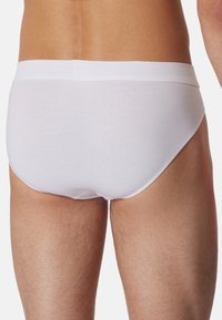 Witte katoenen slip met een zachte textuur en elastische tailleband, voorzien van een minimalistisch ontwerp en een comfortabele pasvorm.