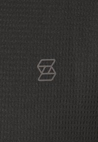 Black textured fabric with a subtle, woven pattern and a gray logo featuring overlapping shapes positioned at the bottom right.