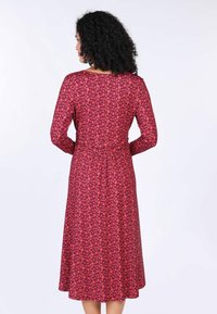 Langärmliges Kleid aus rotem Stoff mit floralen Mustern. Die Taille ist tailliert, und der Saum endet unter dem Knie und besitzt eine lockere Silhouette.