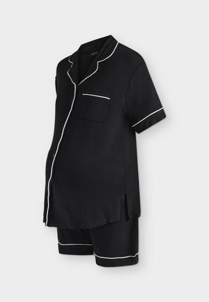 Pyjama de maternité noir avec manches courtes et short, doté d’un passepoil blanc sur le col, la poche, les poignets et les ourlets.