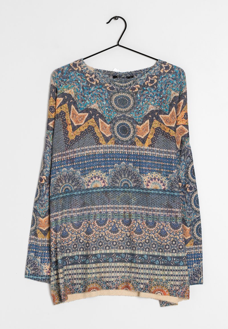 Pull en maille à manches longues avec motifs géométriques et floraux multicolores complexes en tons bleus, orange et beige, suspendu sur un cintre noir sur fond blanc.