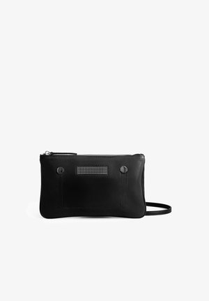 Zwarte leren tas met een minimalistisch design, voorzien van een ritssluiting, hexagonale hardware-accenten en een gestructureerde patch aan de voorkant.