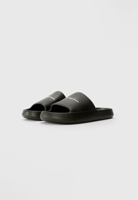 Sorte svarte sandaler laget av glatt gummi, med åpen tå, brede stropper og preget logo på overdelen. Teksturert såle for godt grep.