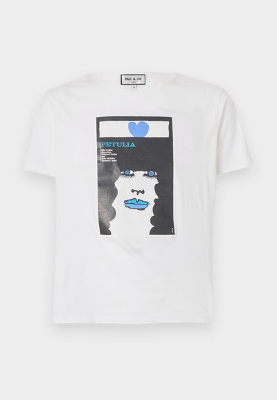Balta medvilninė marškinėlių su grafiniu atspaudu, vaizduojančiu veidą su juodais garbanotais plaukais, mėlynomis lūpomis ir mėlynu širdelė, su įtrauktomis teksto elementais.