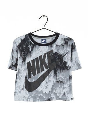 Koszulka Nike z krótkim rękawem w czarno-biały abstrakcyjny wzór, duże czarne logo Nike i okrągły czarny kołnierz na wieszaku.