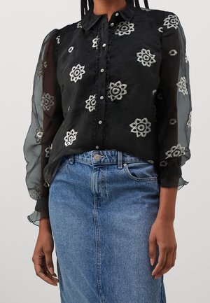 Blouse noire transparente avec broderie florale en argent. Dotée d'un col classique, d'une fermeture à boutons et de détails froncés le long de la patte de boutonnage.