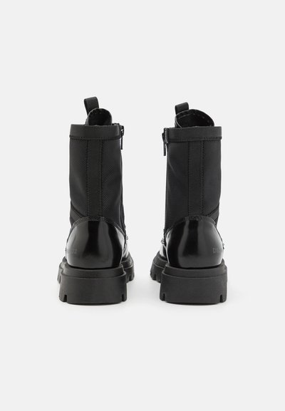 Melnas potītes botas, izgatavotas no gludām un teksturētām materiālu, ar masīvu zoli, rāvējslēdzēja aizdari un izvelkamām cilpām aizmugurē ērtai uzvilkšanai.