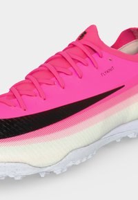Φωτεινό ροζ αθλητικό παπούτσι Nike Flyknit με μαύρο λογότυπο swoosh, ροζ κορδόνια και λευκή υφή στη σόλα.