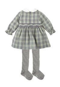 Vestido de cuadros verdes con cuello blanco, mangas cortas y falda con vuelo. Acompañado de medias gris. La tela es mezcla de algodón.