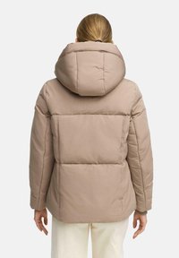 Puffer jacket in light beige with a large hood, featuring quilted sections, long sleeves, and a relaxed fit. Textured fabric finish.
