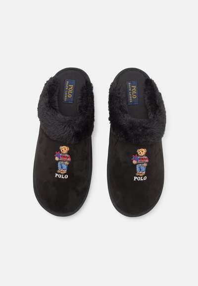 Melni zamšveida čības ar pūkainu melnu apkakli, ar izšūtu lāci džemperī un džinsos, kā arī "Polo" zīmola detaļu.