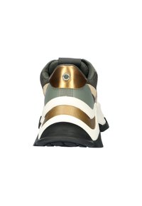 Sneaker mit einem runden, goldenen Akzent an der Ferse, olivgrüner und cremiger Oberseite, strukturiertem Stoff und schwarzer Gummisohle.