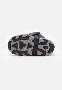 Suela de sandalia infantil en negro y gris con un patrón de tracción resistente, que confirma un diseño robusto y flexibilidad para su uso al aire libre.