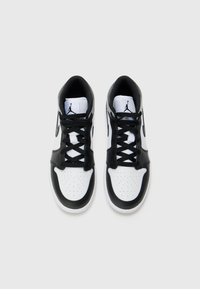 Mustvalged mustad ja valged kõrge põlvega tennisetossud, millel on augulised varbad, siledast nahast materjal, mustad paelad ja Jumpman logo keele peal.