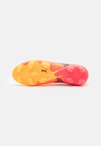 Calzado Puma con una suela segmentada en tonos brillantes de naranja y rosa. Presenta patrones texturizados y elementos de tracción de goma prominentes.