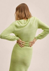 Jasnozielona sukienka z prążkowanej tkaniny z długimi rękawami, dopasowanym krojem i teksturowanym materiałem. Z tyłu ma dekolt w serek i zaakcentowaną talię.