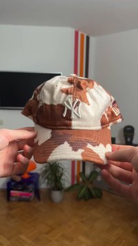 Baseballkappe mit Tarnmuster in Beige- und Weißtönen, mit aufgesticktem Logo und strukturiertem Schirm. Die Textur wirkt weich.