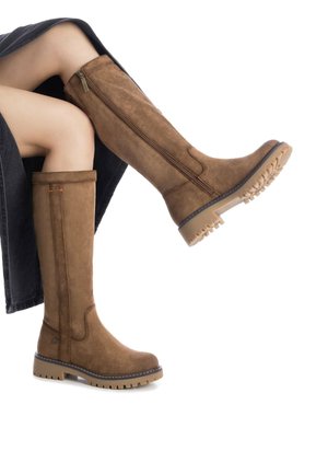 Botas de ante marrón hasta la rodilla con suela de goma plana, cremallera lateral y costuras decorativas. Superficie texturada con un acabado limpio.