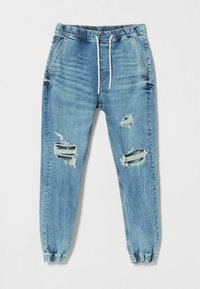Pantalones jogger de mezclilla azul claro con cintura elástica y cordón. Presenta desgastes con secciones rasgadas en las rodillas y puños ajustados.