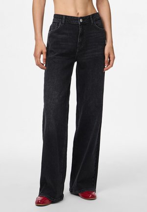 Black wide-leg jeans made of denim, featuring a high waist, front pockets, and a button closure. Worn with red shoes.