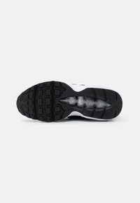 Shoe sole featuring a black rubber grip with square and rectangular patterns, designed for traction. Overall white and black color scheme.