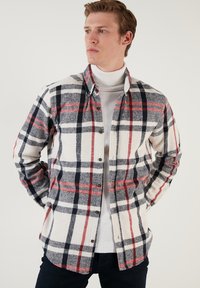 Ruitjes flanellen shirt in crème, marineblauw en rood. Gemaakt van zachte stof, voorzien van knopen, lange mouwen en een klassiek kraagontwerp.
