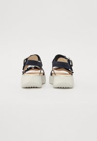 Navy blue suede sandals with two adjustable straps, silver buckles, and a white thick platform sole with tread detailing.