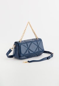 Laukkua navy sinisestä nahasta, jossa on tikattu kuvio, kultaketju ja hihna, suorakulmainen muoto sekä sileä pinta. Varusteena säädettävä hihna.