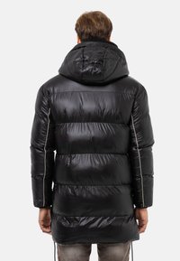 Schwarze Pufferjacke mit Kapuze, ausgestattet mit einer glänzenden, gepolsterten Textur, vertikalen Nähten und kontrastierenden Seitenpipings.
