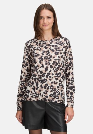 Leopardenmuster Pullover mit Rundhalsausschnitt aus weichem Strickstoff, mit beigen und schwarzen Punkten, kombiniert mit schwarzen Lederhosen. Lange Ärmel.