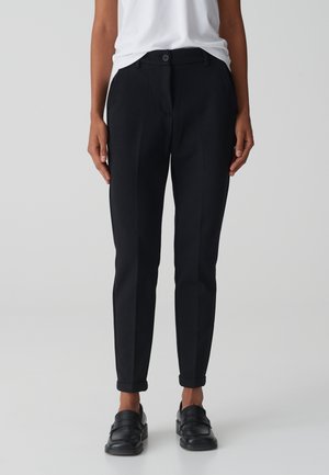 Black tailored trousers with a front button closure, tapered legs, and roll-up cuffs. Made from a smooth, textured fabric.